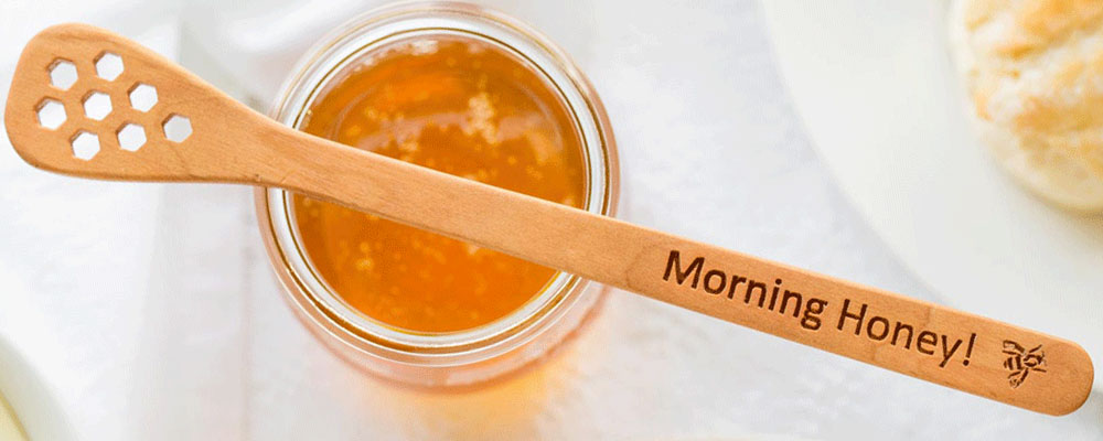 Honey stick laying over a jar of honey